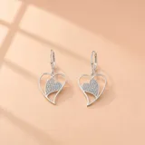 Caravanas colgantes de plata 925 con diseño de corazón calado y un corazón interior pavé con incrustaciones de circonias brillantes.