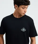 Remera negra de manga corta y cuello redondo, confeccionada en algodón y poliéster. Cuenta con un pequeño estampado localizado en el pecho y un diseño gráfico de mayor tamaño en la espalda.