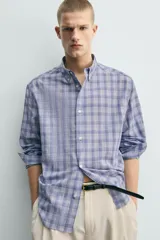 Camisa de corte relajado confeccionada en tejido de algodón, con estampado de cuadros en tonos azules. Presenta cuello abotonado, manga larga con puños abotonados y cierre frontal con botones.