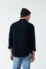 Camisa de pana color beige, de corte regular, con cuello clásico y cierre frontal con botones. Confeccionada en algodón.