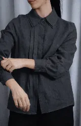 Camisa de lino color tostado con diseño de doble cuello, cartera escondida y tablas frontales que aportan movimiento. Presenta mangas largas y un corte versátil.