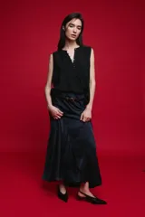 Blusa sin mangas color negro, de silueta fluida, con cuello redondo, detalle de alforzas en el frente y abotonadura parcial con botones visibles.
