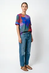 Remera de silueta relajada con estampa pictórica abstracta en tonos azul, rojo, verde y violeta.