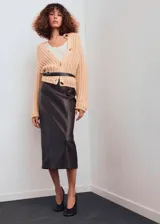 Cardigan de punto grueso color beige, de cuello redondo, manga larga y diseño recto. Presenta cierre frontal con botones efecto joya.