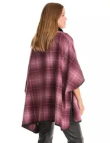 Ruana de tejido suave, color beige y marrón con estampado geométrico repetitivo. Posee cuello con aplique de piel sintética marrón y ribetes negros. Se combina con un suéter marrón de manga larga con botones en el puño.