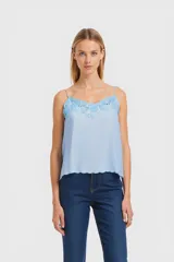 Musculosa celeste con breteles finos y detalle de encaje floral en el escote.