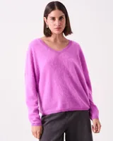 Sweater de cachemire color fucsia, de silueta relajada con escote en V, puños y ruedo corto. Presenta un material extra suave tipo pelo.