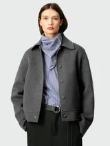 Chaqueta corta gris de lana con corte cuadrado, cuello clásico, cierre abotonado y bolsillos de parche.