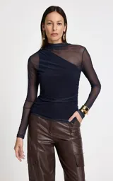 Blusa de manga larga confeccionada en microtul azul marino, con cuello alto y diseño ajustado. Presenta un corte asimétrico en el escote y detalles drapeados en el lateral, con transparencias en mangas y hombros.