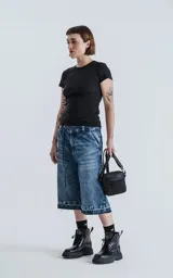 Bermuda larga de denim azul con lavado ácido y efecto desgastado. Presenta un calce oversize, talle alto con cinturón de tela a juego y ruedos deshilachados.