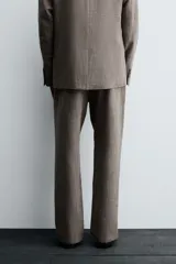 Pantalón de traje de corte slim fit, color marrón con textura sutil. Cuenta con cierre frontal de cremallera y botón, bolsillos laterales y bolsillos traseros de doble vivo con botón.