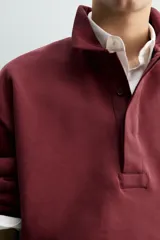 Polo boxy fit color bordó, confeccionado en tejido de algodón. Presenta cuello solapa, cierre frontal con botonadura oculta por solapa y manga larga.