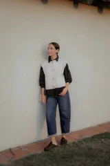 Chaleco de punto en color marrón oscuro, con cuello redondo y cierre frontal mediante botones metálicos decorativos con forma de sol.