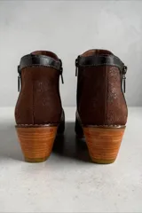 Botas cortas de cuero marrón jaspeado con detalles pintados a mano en tonos dorados, con taco cuadrado de altura media, punta fina y cierres laterales decorativos.