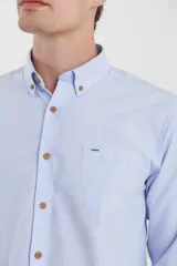 Camisa de vestir blanca de manga larga, con cuello abotonado, bolsillo frontal y botones en tono madera.