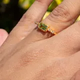 Anillo dorado con una piedra central rectangular de color verde claro (peridoto) y dos diamantes a cada lado. Elaborado en plata 925 bañada en oro 18k.