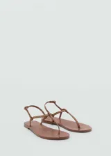 Sandalia de cuero color marrón con diseño de tiras finas y pequeñas tachuelas doradas. Cierre con hebilla.