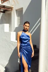 Vestido midi de satén color violeta, con escote asimétrico, falda con abertura lateral y detalle drapeado en la cintura. Incluye un cuello tipo choker que se puede usar de diferentes formas.