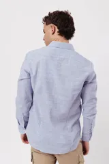 Camisa de manga larga para hombre, color azul claro jaspeado, con cuello clásico y botones blancos. Corte ajustado (slim fit).
