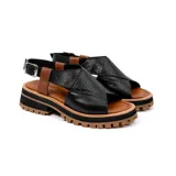 Sandalia de cuero vacuno color negro, con suela de goma deportiva, hebilla al tobillo y horma ancha.