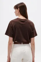 Remera de manga corta de algodón en color blanco, con cuello redondo y diseño holgado. Presenta un estampado frontal con detalle de acabado metálico (foil).