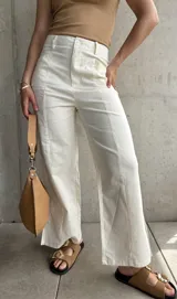 Pantalón de lino color crudo, de corte recto, con pinzas en la cintura y aberturas laterales en el ruedo.