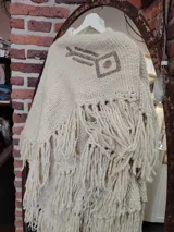 Ruana color crema tejida en lana merino con bordados a mano sobre lino.