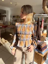 Blusa de manga larga con diseño de cuadros en tonos camel y azul, confeccionada con tejido elástico fruncido en todo el cuerpo y las mangas.