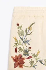 Bermuda color crudo confeccionada en algodón y lino, con tiro medio, cintura elástica ajustable con cordones y bordado floral a contraste en los laterales.