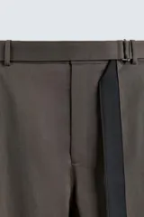 Pantalón de corte wide fit confeccionado en tejido con algodón. Presenta pliegues frontales, cintura ajustable con cinturón integrado, bolsillos laterales y bolsillos traseros de vivo. Cierre frontal con cremallera y botón.