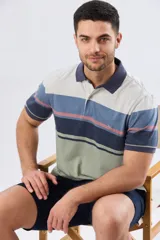 Remera polo de manga corta con diseño a rayas horizontales en tonos beige, celeste, rosado, azul marino y verde. Cuenta con cuello polo y cierre frontal con botones.