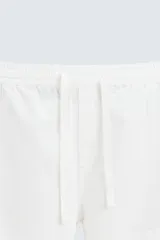Pantalón de corte relajado color beige confeccionado en tejido de mezcla de algodón y lino. Posee cintura elástica ajustable con cordón, bolsillos frontales y bolsillos traseros de vivo.