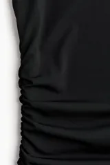 Vestido midi negro de punto elástico, con escote bote, mangas japonesas y frunces laterales que ajustan la silueta.