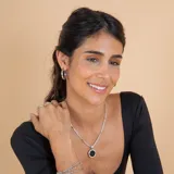 Collar con cadena de eslabones trenzados en plata con detalles en oro, que sostiene un dije circular con piedra ónix negra central y borde en oro.