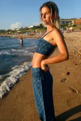 Top corto de denim azul con estampado de monogramas, escote recto, breteles finos y cierre en la espalda.