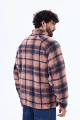 Campera de sherpa con diseño a cuadros en tonos marrón y azul marino. Presenta cuello alto, cierre frontal parcial y un bolsillo frontal con cierre en contraste de color azul marino.