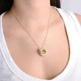 Collar dorado con cadena fina y dije de dos aros entrelazados, uno liso y otro con incrustaciones de cristales.