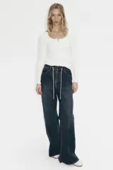 Top de manga larga en punto acanalado de algodón con diseño pointelle, escote en U con ribete festoneado y tapeta con botones al frente.