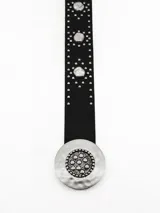 Cinto negro de cuero sintético con tachas metálicas plateadas y hebilla circular grande con diseño texturizado.