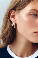 Pendientes metálicos dorados en forma de medio aro doble con aplicación de perla a contraste.