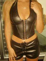 Top negro tipo corset confeccionado en cuero sintético, con escote halter y cierre frontal con ganchos metálicos.