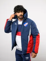 Campera de abrigo Umbro del Club Nacional de Football, con diseño de bloques de color en azul, blanco y rojo. Cuenta con capucha ajustable, cierre frontal y logo de la marca junto al escudo del club en el pecho.