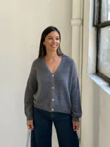 Saco tipo cardigan de punto color gris, con escote en V, cierre frontal de botones y puños y ruedo acanalados.