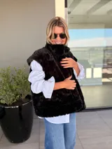 Chaleco reversible con un lado de piel sintética gris y el otro lado de tela bordada con diseño floral y espiral en tonos blanco y negro. Presenta un diseño sin mangas y corte recto.