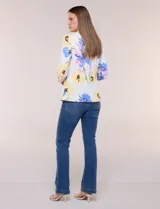 Blazer de silueta semientallada confeccionado en tela sastrera de color blanco con estampado floral en tonos amarillos, celestes, rosados y azules. Presenta solapa de muesca clásica, acceso frontal mediante un botón a tono, bolsillos simulados con solapa y mangas largas de corte clásico.