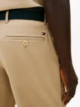 Pantalón corto beige tipo chino de Tommy Hilfiger, con bolsillos laterales y traseros, confeccionado en sarga de algodón y elastano. Incluye trabillas para cinturón.