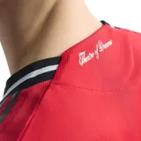 Camiseta de fútbol Adidas del Manchester United, modelo Local 25/26. Diseño rojo con detalles negros y blancos en cuello y mangas. Incluye logo de Adidas, escudo del club y sponsor Snapdragon en el frente.