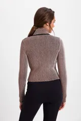 Campera corta de tejido de punto acanalado con diseño de rayas verticales en dos tonos. Presenta cuello alto y cierre frontal completo con borde en color negro.