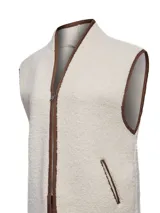 Chaleco de polar tipo corderito en color beige, con cierre frontal y detalles de ribetes en color marrón. Presenta bolsillos laterales y un diseño sin mangas.