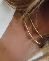 Aros tipo argolla grandes, de metal dorado. Diseño minimalista y elegante.